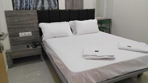 塞恩Hotel Sai Nidhi Residency的一张带黑色床头板和白色枕头的白色床