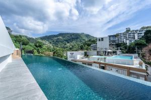 an infinity pool at a hotel with mountains in the background at Palmetto Park Residence in Karon Beach