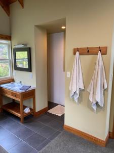 a bathroom with a sink and towels hanging on the wall at Above the Bay in Hahei +61 photos