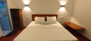 a bedroom with a bed with white sheets and two lights at Ayuvilla in Goiyapana