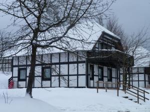 een gebouw in de sneeuw met een boom bij House of Rootz in Frankenau
