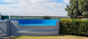 a blue swimming pool in a yard next to a fence at Die Speelkamer in Bredasdorp