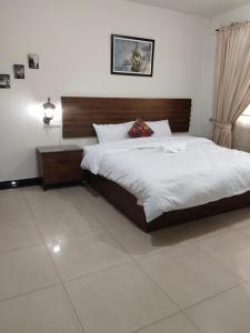 a bedroom with a large bed with a wooden headboard at Lovely 2-Bedroom Apartment in Lahore