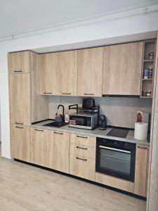 eine Küche mit Holzschränken und einer Mikrowelle in der Unterkunft Family Apartament Mamaia in Mamaia Nord – Năvodari