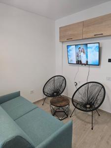 Zimmer mit einem Bett, 2 Stühlen und einem Flachbild-TV in der Unterkunft Family Apartament Mamaia in Mamaia Nord – Năvodari