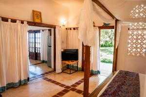 a living room with a television and a window at Mawimbi Cottage in Ukunda