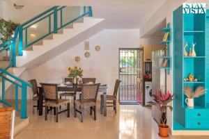 カンドリムにあるStayVista at The Zen Zone with Pool, BBQ, WiFiのダイニングルーム(テーブル、椅子、階段付)