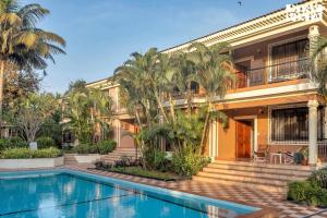 a villa with a swimming pool in front of a house at StayVista at The Zen Zone with Pool, BBQ, WiFi in Candolim