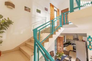 a staircase in a home with a blue railing at StayVista at The Zen Zone with Pool, BBQ, WiFi in Candolim