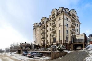 Un gran edificio con coches aparcados delante. en MARION Family Resort, en Bukovel