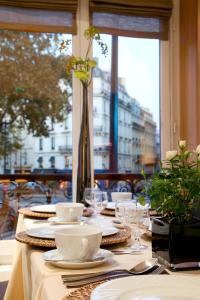 a table with plates and dishes on a table with a window at Marceau Champs-Elysées in Paris
