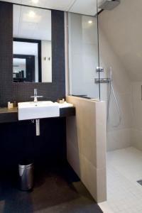 a bathroom with a sink and a shower with a mirror at Marceau Champs-Elysées in Paris