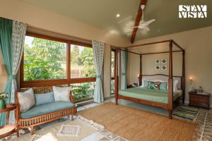 a bedroom with a canopy bed and a couch at StayVista at Ridgewood Mansion with BBQ, Gazebo & Infinity Pool in Pune