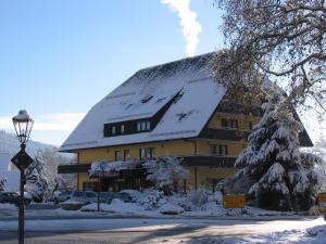 a large yellow building with a snow covered roof at Hotel Sonne in Zell am Harmersbach