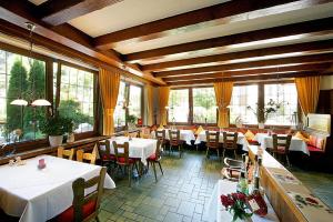 un ristorante con tavoli e sedie bianchi e finestre di Hotel Sonne a Zell am Harmersbach