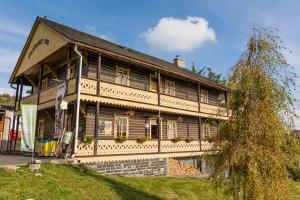 une grande maison en bois avec un arbre en face de celle-ci dans l'établissement Švajčiarsky Dom, à Starý Smokovec