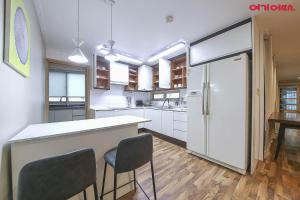 a kitchen with a white refrigerator and two chairs at BOBOS Hotel in Jeju
