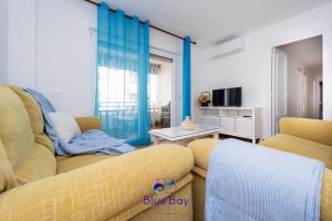 Una sala de estar con dos sofás amarillos y un televisor. en At The Plaza Central Beach Flat, en La Herradura
