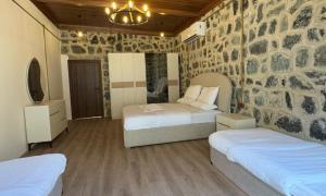 a bedroom with two beds and a stone wall at The Out Resort in Sinādil