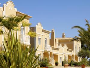 a large yellow building with palm trees in the foreground at Vila Alba Resort in Carvoeiro