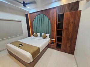 a bedroom with a bed with a wooden headboard at Hotel M Grand in Miriālgūda