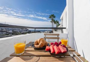 a table with fruit and croissants and orange juice at Apartment with sea view and pool in Puerto Rico de Gran Canaria
