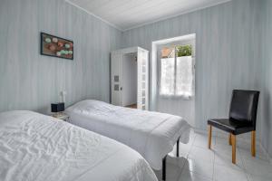 a bedroom with two beds and a chair and a window at Plage à 200m, maison mitoyenne de plain-pied, 4 pers in La Bernerie-en-Retz