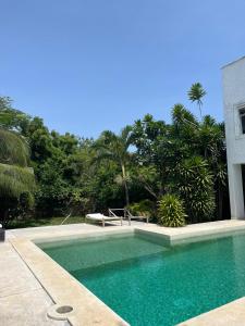 a swimming pool in front of a house with trees at Ripasso Bed & Breakfast in Malindi
