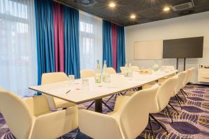 a conference room with a table and chairs and a screen at Prize by Radisson, Erfurt City in Erfurt