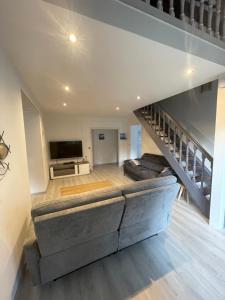 a living room with a large couch and a staircase at Maison familiale au cœur du bassin d'Arcachon in Biganos