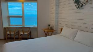 a bedroom with a bed and a table and a window at Jeju Stay Haven in Jeju