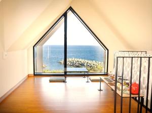 a large window in a room with a view of the ocean at Seogwipo Hineni Private House in Seogwipo