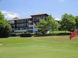 einen Golfplatz mit Hotel im Hintergrund in der Unterkunft Appt vue golf dans résidence avec piscine in Bassussarry