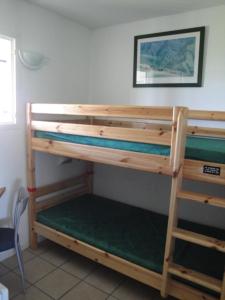 ein Etagenbett aus Holz in einem Zimmer mit Fenster in der Unterkunft Appt vue golf dans résidence avec piscine in Bassussarry
