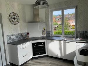 a kitchen with white cabinets and a sink and a window at Le BerNid Gîte et SPA in Triembach-au-Val