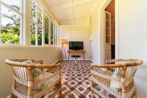 a hallway with two wicker chairs in a room with windows at La Garçonniere in Saint-Pierre