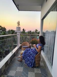 a woman sitting in a chair on a balcony at Choudhury's Stay Barpeta Road in Helāpākari