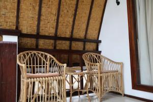 two wicker chairs and a table in a room at Rumah Gemala Gili Air in Gili Air