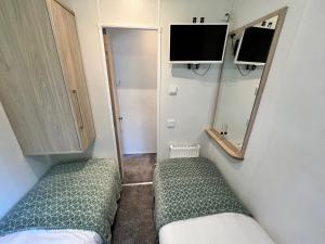 a small room with two beds and a mirror at 3 Bedroom Caravan LG34, Lower Hyde, Shanklin in Shanklin