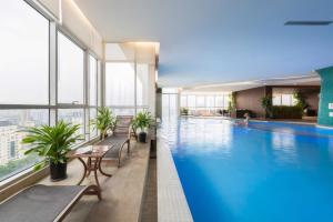 a large swimming pool in a building with windows at SIMI Homes Lancaster 24 Cozy Studio for 4 in Luxury Building with Heated Pool, Fitness and Spa Hanoi Center in Hanoi