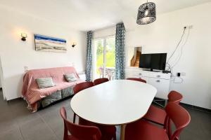 a living room with a white table and red chairs at Maisonnette tout confort - Golf - Piscine in Quéven