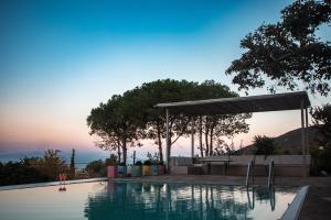 a swimming pool with a sunset in the background at Hippie Bay Complex in Porto Rafti