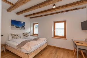 a bedroom with a bed and a desk and windows at Ciesa dela Maestra in Rocca Pietore