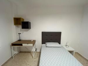 a small bedroom with a bed and a desk at VUT Parque II TORREON 4 dormitorios y 2 baños Parking gratuito cercano in Ciudad Real