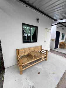 un banco de madera sentado junto a una pared blanca en Beach Bungalows, en Thong Sala