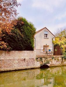 a house on a brick wall next to a river at Petite maison centre-ville in Nemours