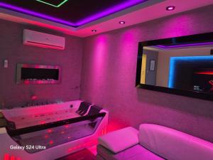 a pink room with a tub and a tv at Apartament Miami in Ełk +2 photos