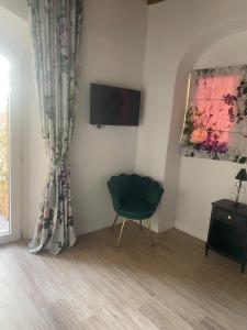 フィレンツェにあるIl Portico di Margheritaの緑の椅子とテレビが備わる客室です。