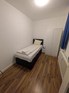 a small bedroom with a bed and a wooden floor at 1,5-Zimmer Apartment mit Balkon am Hauptbahnhof in Neumünster