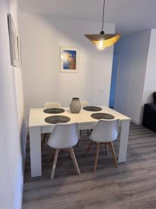 a white dining room table with four chairs and a vase on it at Apartamento céntrico de estilo nórdico in Adeje +15 photos